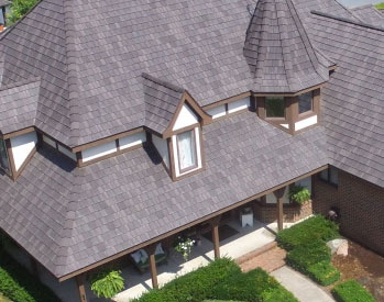 Front view of large residential home with a front porch and brown DaVinci roof tiles